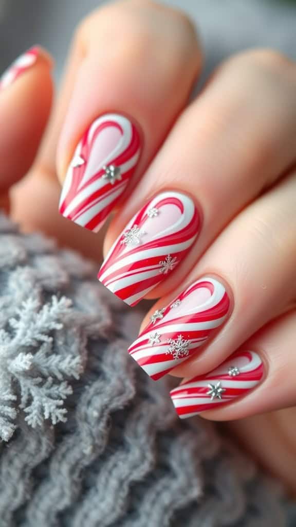Close-up of hands showing nails painted with red and white candy cane stripes and adorned with silver snowflake decorations, against a background of a gray knitted sweater with snowflake patterns.
